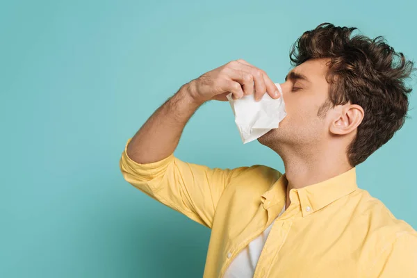 Man blowing out nose with napkins on blue — Stock Photo