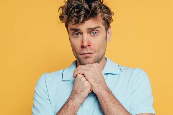 Portrait of sad and sick man with clenched hands looking at camera isolated on yellow — Stock Photo