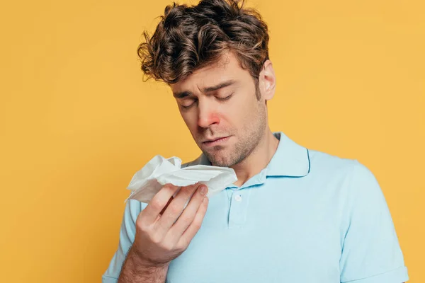 Portrait of sick man with napkins and closed eyes isolated on yellow — Stock Photo