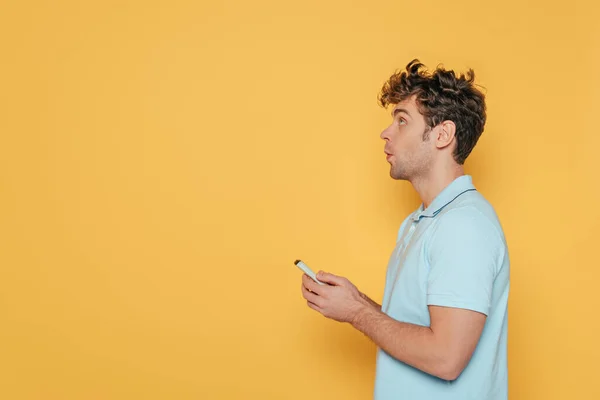 Vue latérale de l'homme tenant la télécommande isolée sur jaune — Photo de stock