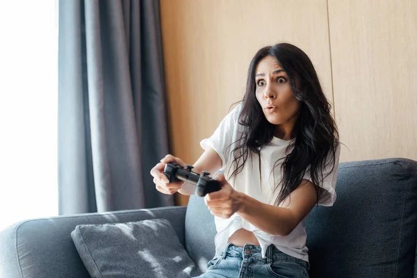 KYIV, UKRAINE - APRIL 9, 2020: surprised girl playing video game with joystick on self isolation — Stock Photo