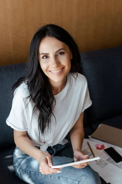 Smiling woman working with digital tablet, smartphone and business documents on sofa — Stock Photo