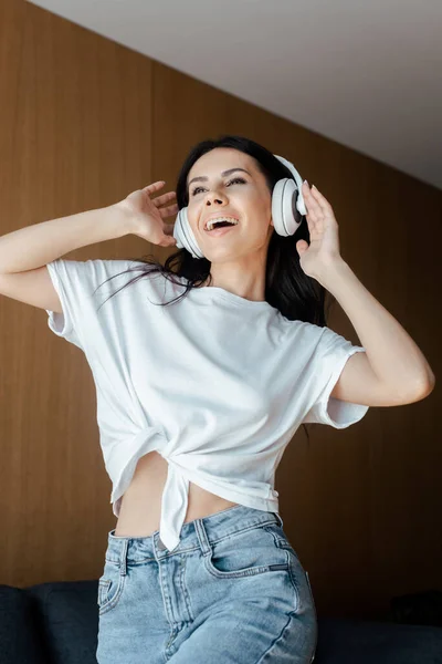 Allegra ragazza ballare e ascoltare musica con le cuffie a casa — Foto stock