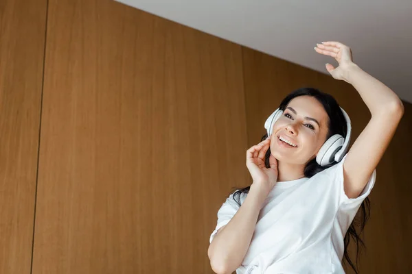 Hermosa chica feliz bailando y escuchando música con auriculares en casa - foto de stock