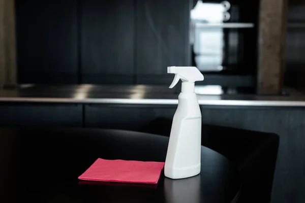 Pano rosa e frasco de spray para limpeza em mesa escura — Fotografia de Stock