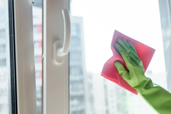 Частковий вид дівчини в гумовій рукавичці очищення віконної ручки з рожевою ганчіркою — стокове фото
