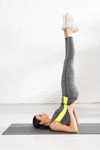 Side view of attractive sportswoman doing birch exercise on fitness mat — Stock Photo