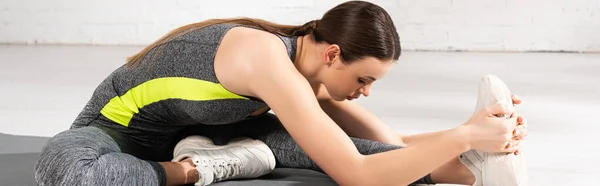 Panoramic orientation of young and attractive sportswoman warming up on fitness mat — Stock Photo