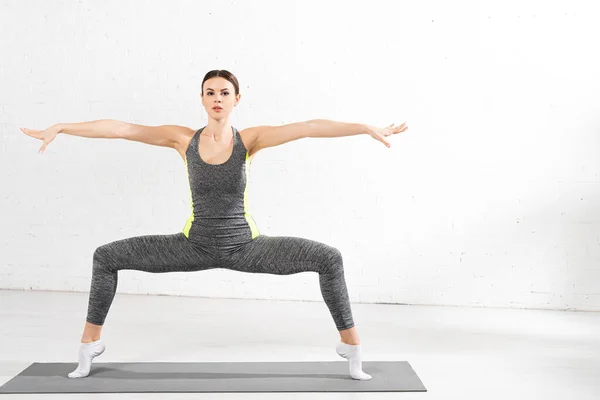 Chica atlética con las manos extendidas haciendo ejercicio en la estera de fitness - foto de stock