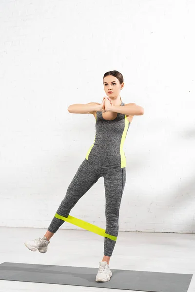 Sportive girl with praying hands exercising with resistance band on fitness mat — Stock Photo