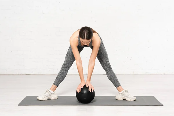 Спортсменка в спортивной одежде тренируется с черным мячом — стоковое фото