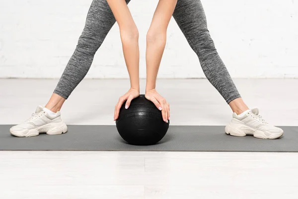 Ausgeschnittene Ansicht einer jungen Frau in Sportkleidung, die mit schwarzem Ball trainiert — Stockfoto