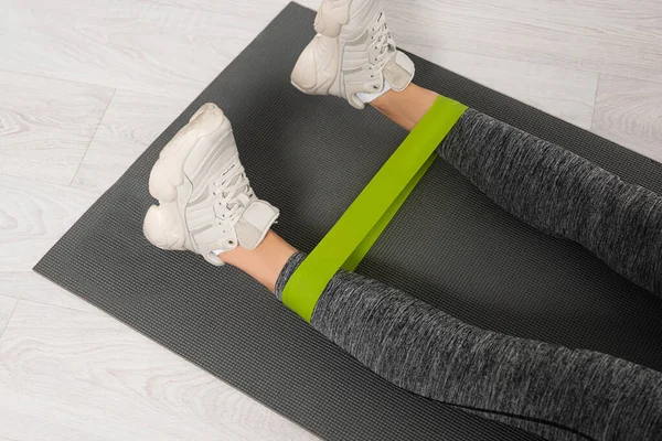 Cropped view of woman working out with resistance band on fitness mat — Stock Photo