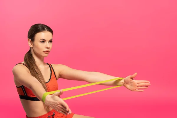 Hermosa deportista haciendo ejercicio con banda de resistencia en rosa - foto de stock