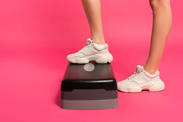 Cropped view of sportswoman standing on step platform on pink — Stock Photo