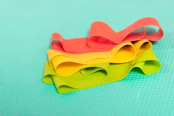 Selective focus of colorful resistance bands on turquoise fitness mat — Stock Photo