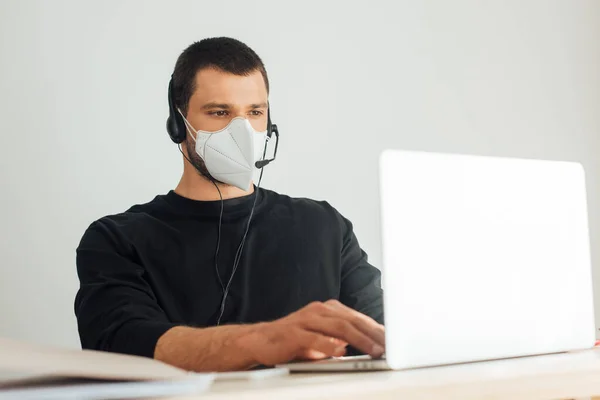 Foyer sélectif de l'opérateur dans le masque médical et casque de travail de la maison avec ordinateur portable — Photo de stock