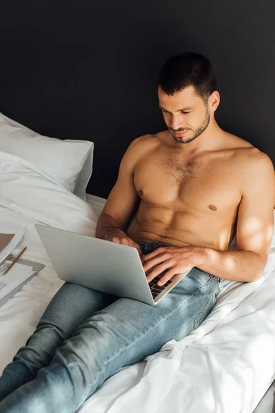 Handsome and shirtless freelancer using laptop in bedroom — Stock Photo