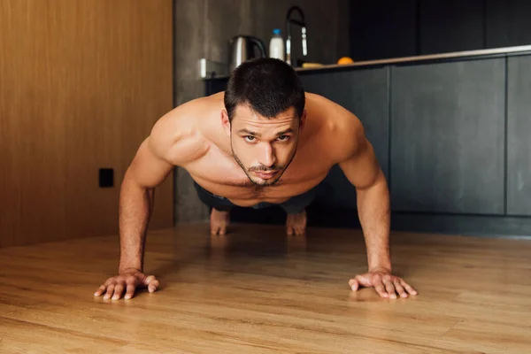 Hombre barbudo y musculoso haciendo ejercicio de tablón en casa - foto de stock