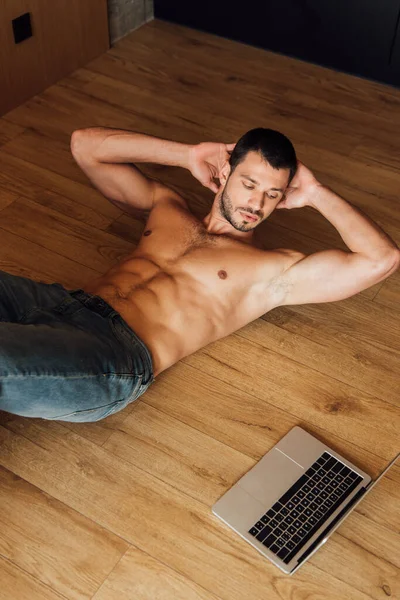 Top view of muscular man exercising while watching online training on laptop — Stock Photo