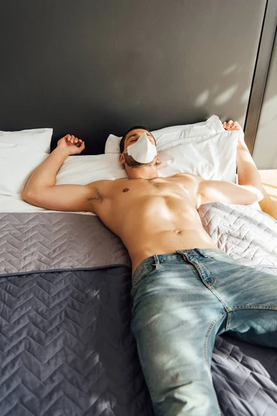 Muscular man in medical mask sleeping on bed — Stock Photo