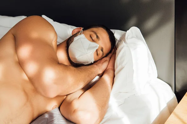 Muscular man in medical mask sleeping in bedroom — Stock Photo