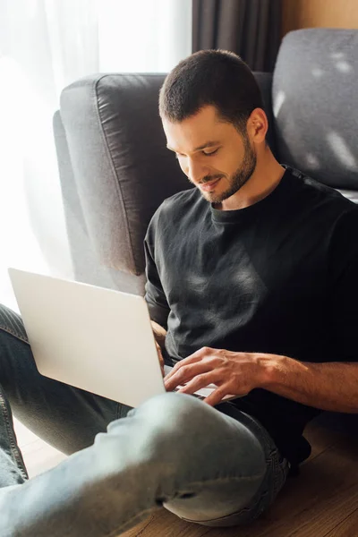 Joyeux et barbu pigiste en utilisant un ordinateur portable à la maison — Photo de stock