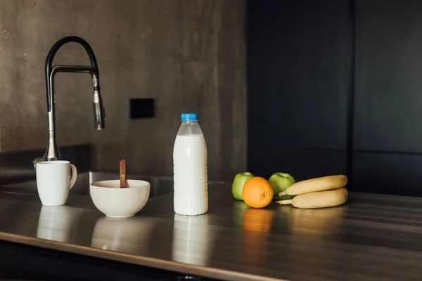 Tasty fruits near bowl with spoon and bottle of milk — Stock Photo