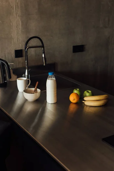 Deliciosas frutas perto de tigela com colher e garrafa de leite — Fotografia de Stock