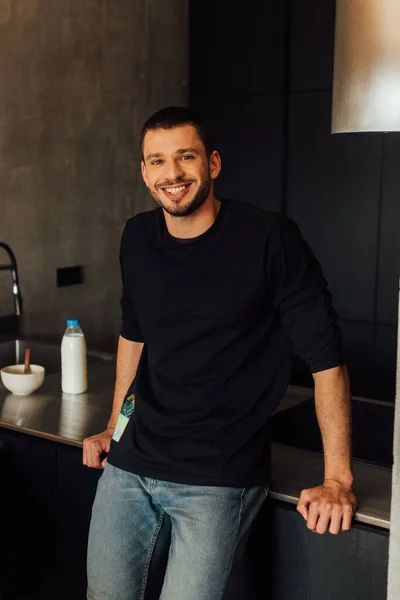 Felice uomo barbuto sorridente e guardando la fotocamera in cucina — Foto stock