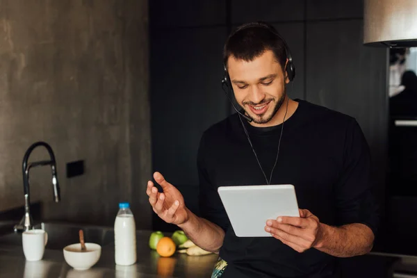 Feliz freelancer en auriculares usando tableta digital en casa - foto de stock