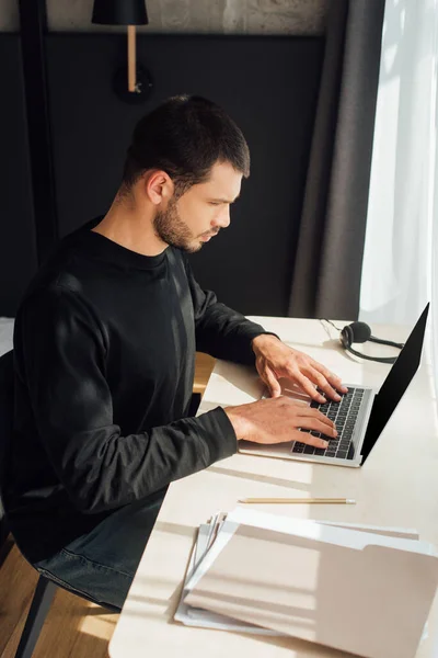 Freelance barbuto utilizzando computer portatile vicino alla cartella a casa — Foto stock