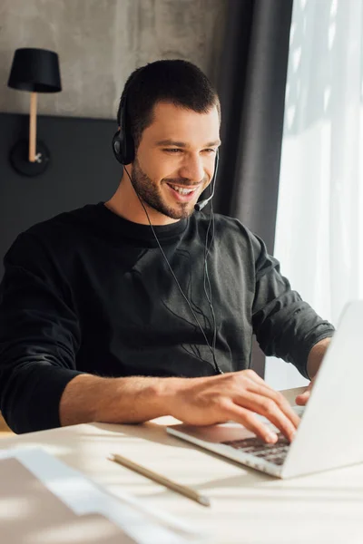 Selective focus of happy operator in headset using laptop at home — Stock Photo