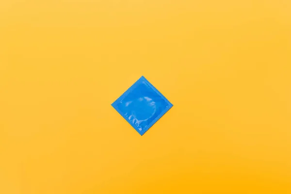 Top view of blue pack with condom isolated on orange — Stock Photo