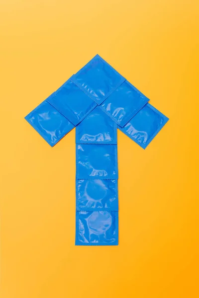 Vista superior de flecha de embalagens com preservativos isolados em laranja — Fotografia de Stock