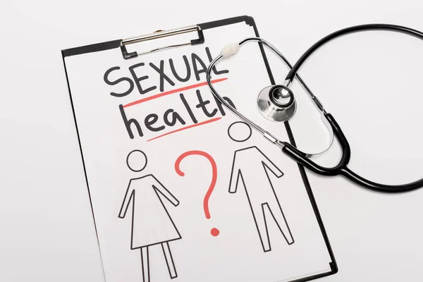 Draufsicht auf Klemmbrett mit Schriftzug Sexuelle Gesundheit, gezeichnet Mann und Frau in der Nähe von Stethoskop isoliert auf weiß — Stockfoto