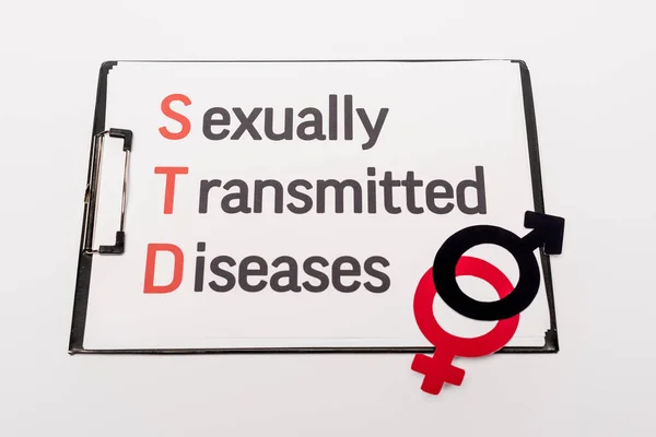 Top view of clipboard with sexually transmitted diseases near gender symbols isolated on white — Stock Photo