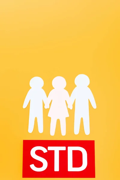 Top view of three paper people near red paper with std lettering isolated on orange — Stock Photo