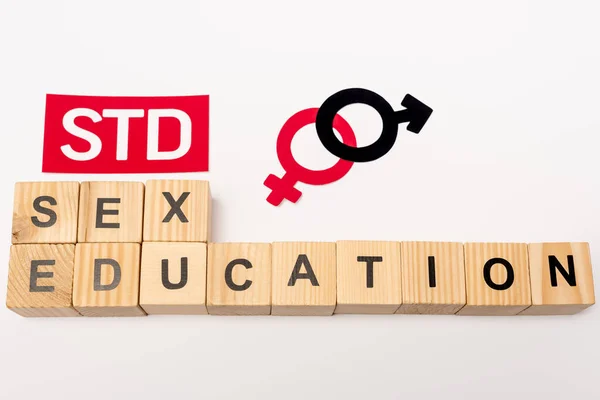 Top view of wooden cubes with sex education near paper with std lettering and gender symbols isolated on white — Stock Photo