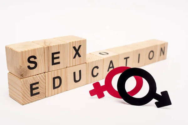 Selective focus of wooden cubes with sex education lettering near gender symbols on white — Stock Photo