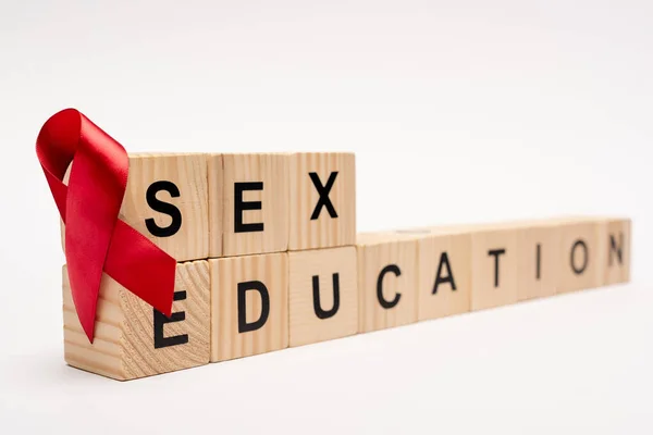 Selective focus of wooden cubes with sex education lettering near red ribbon on white — Stock Photo