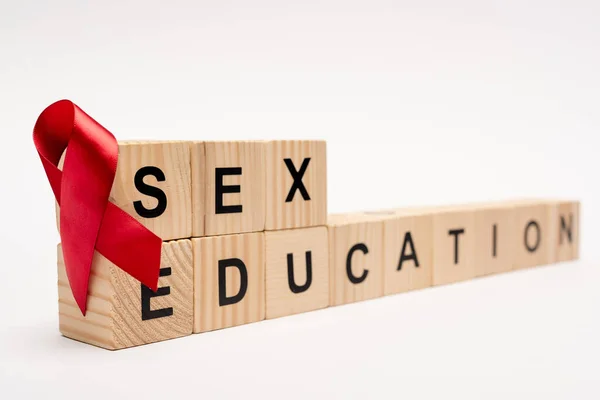 Selective focus of wooden cubes with sex education lettering near red ribbon on white — Stock Photo