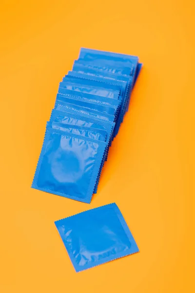 Preservativos em embalagens azuis isoladas em laranja — Fotografia de Stock