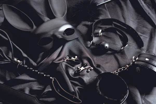 Máscara de coelho perto de brinquedos sexuais em tecido de seda preta — Fotografia de Stock
