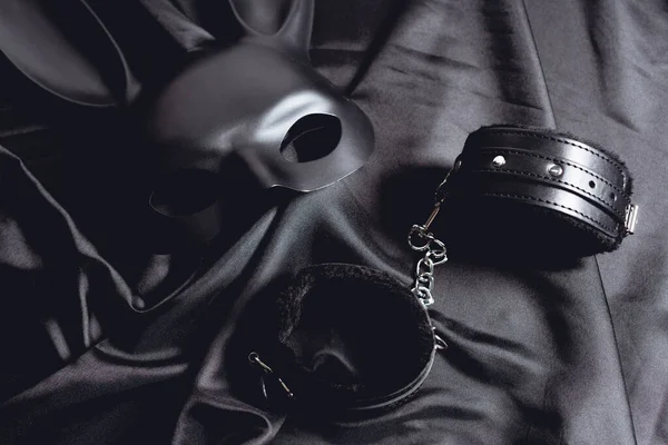 Máscara de coelho perto de algemas de couro em tecido de seda preta — Fotografia de Stock