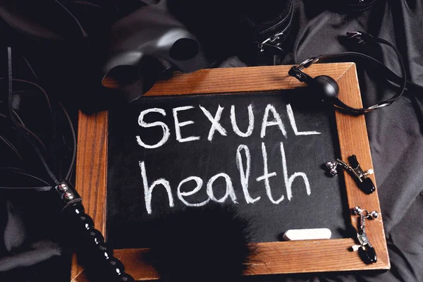 Маска для кроликів біля крейди з написанням сексуального здоров'я та секс-іграшками на чорному шовку — стокове фото