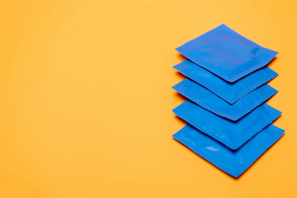 Selective focus of blue packs with condoms isolated on orange with copy space — Stock Photo