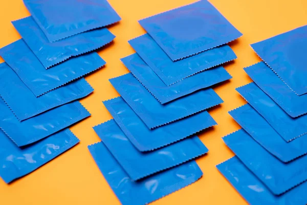 Selektive Fokussierung der blauen Packungen mit Kondomen isoliert auf orange — Stockfoto