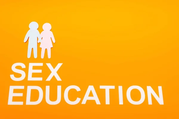 Top view of sex education lettering near paper people isolated on orange — Stock Photo