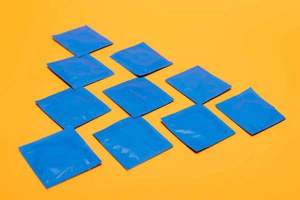 Tendido plano con condones en paquetes azules aislados en naranja - foto de stock